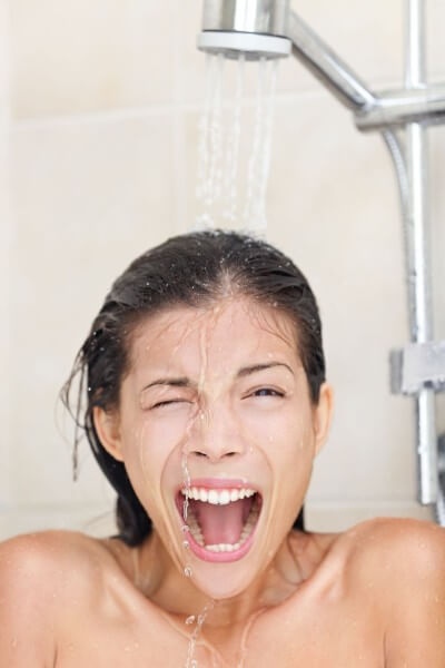 woman making a shocked face under a shower head