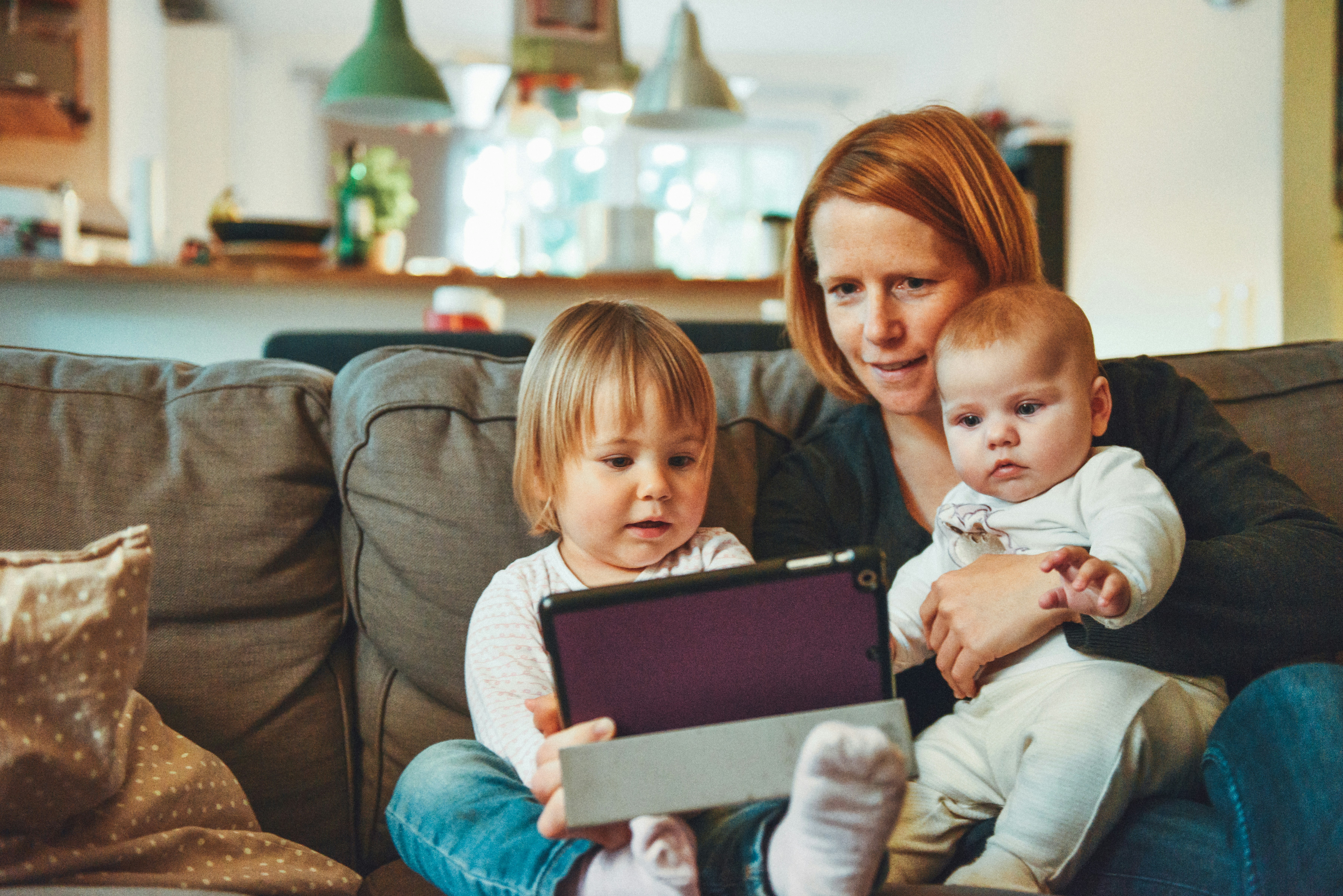 woman and two young children looking at tablet