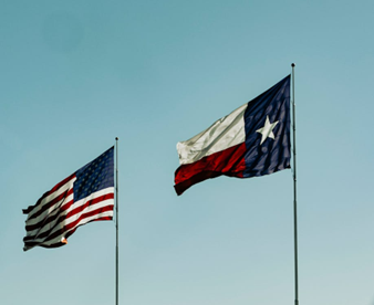 American and Texan flags waving in the wind, representing the home location of Barbosa Plumbing & Air Conditioning, your local AC experts.